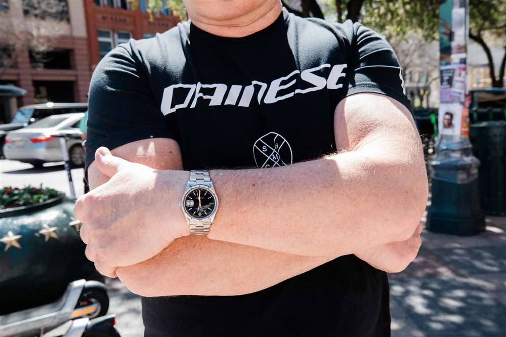 佩戴勞力士手表的雙臂交叉的人。